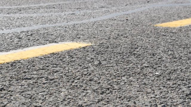 Close up view on asphalt road with an orange marking strip