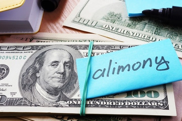Pile of dollars with word alimony on a stick. - obrazy, fototapety, plakaty