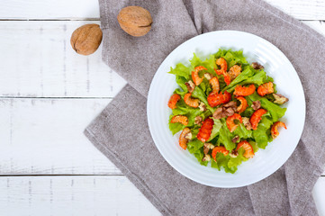 Light dietary spicy salad of lettuce, seafood (crawfish, shrimp) and walnuts on a white wooden background. Top view. Proper nutrition
