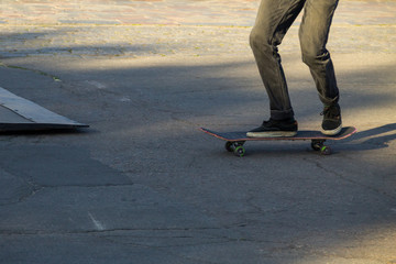 Fototapeta na wymiar Skateboarder legs riding skateboard at skatepark