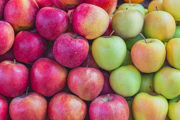 background texture of multi-colored apples stacked on the market counter