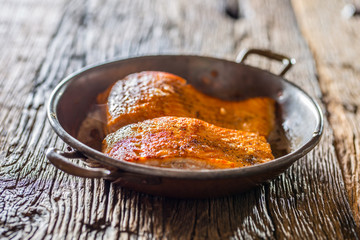 Salmon. Two juicy salmon steaks in roast pan with herb decoration on rustic oak table