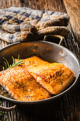 Salmon. Two juicy salmon steaks in roast pan with herb decoration on rustic oak table