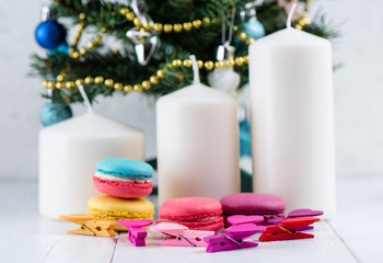 Obraz na płótnie Canvas Sweet and colorful macaroon cookies against a background of candles and Christmas tree