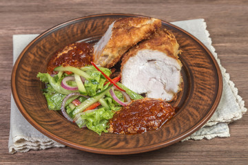Chicken breast with Parmesan cheese, salad and tomato sauce in ceramic bowl closeup. The view from the top. 