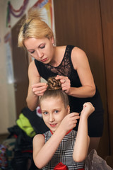 Mom makes daughter hairstyle preparing her for the performance.