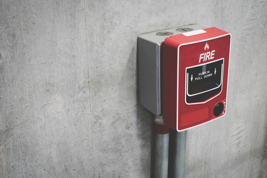 Fire alarm switch on the concrete wall in building for safety with copy space for text. Close-up of fire alarm machine.