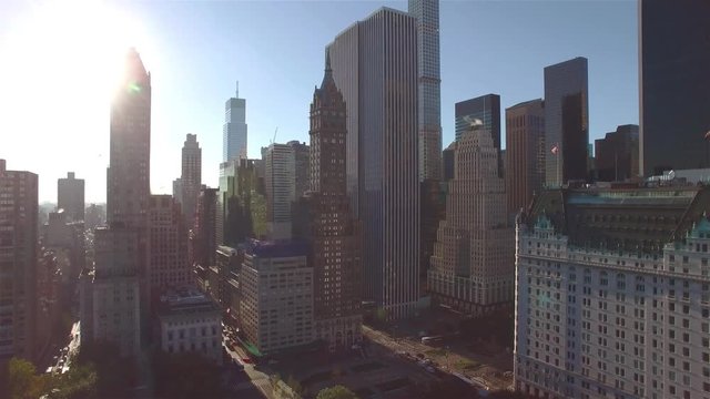 Aerial real time shot, camera is hovering above Central park and filming intersection of West 95th Street and Fifth Avenue in New York. Camera is slowly moving backward.
