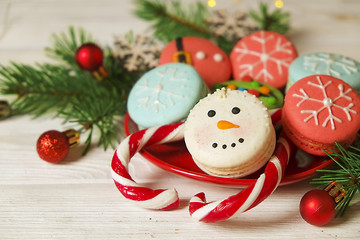 Traditional christmas themed french macaroons sweets in the form of snowman, snowflake, christmas tree and santa's belly with candy cane on the white wooden table.  Close up.