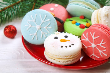 Traditional christmas themed french macaroons sweets in the form of snowman, snowflake, christmas tree and santa's belly with candy cane on the white wooden table.  Close up.