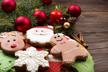 Various types of Christmas gingerbread cookies with fir tree branches, cinnamon sticks, anise star, candle and decoration top view on wooden table with copy space. Christmas holiday sweets food