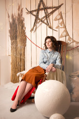 Brunette sitting on a old chair in a denim shirt and brown skirt in vintage interiors
