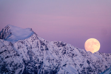 full moon rising in the evening sky in the Swiss Alps over a winter mountain landscape near Klosters - Powered by Adobe