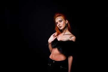 Fashion model red haired girl with originally make up like leopard predator isolated on black. Studio portrait.