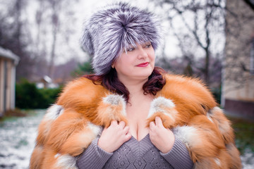 Simple middle age plus size woman wear in knitted dress and fur hat and coat on Arctic weather. Siberia or Norway woman on nature. Plump lady in furs 