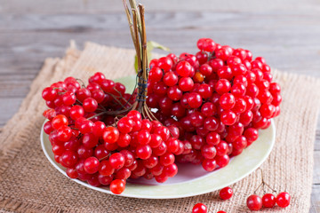 Ripe red berries of a viburnum in a plate on an old wooden table. The source of natural vitamins. Used in folk medicine.