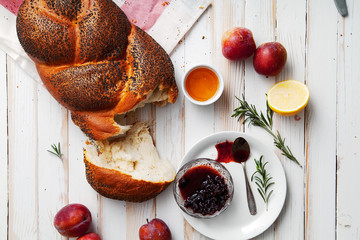 Traditional jewish bread brown challah on white wooden background with fruits and honey. Rustic...