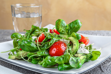 salad with avocado, mozzarella, Basil and cilantro in a beautiful plate stands on the table