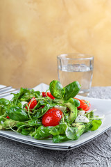 salad with avocado, mozzarella, Basil and cilantro in a beautiful plate stands on the table