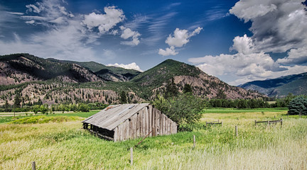 Fototapeta na wymiar Summer sunset with a red barn in rural Montana and Rocky Mountains