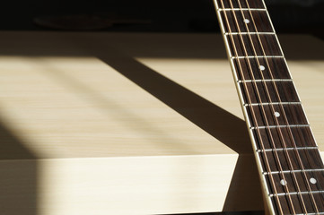 Acoustic guitar neck in sunshine with contrast shadow