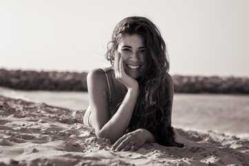 Young woman with long curly hair on sandy beach. Happy and positive female model. Black and white photo