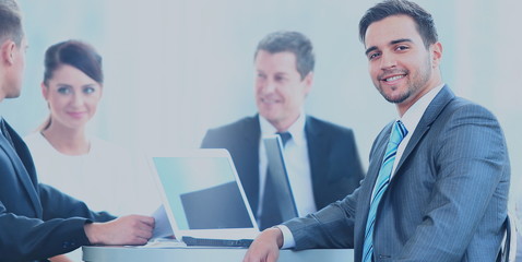 Portrait of mature business man smiling during meeting with colleagues in background