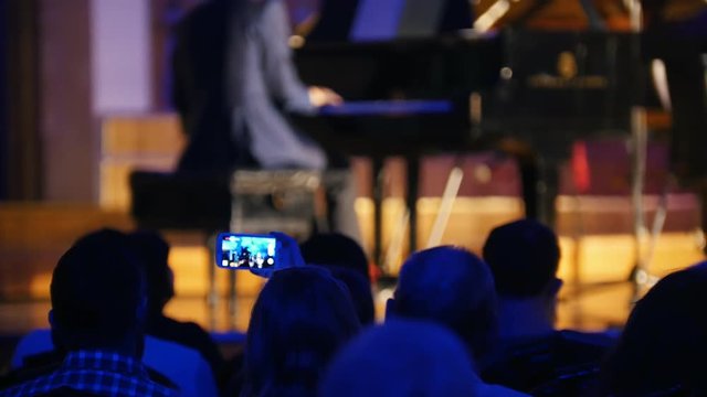 Spectators at concert - people shooting performance on smartphone, scottish musicians