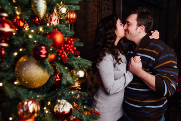 Young couple in love decorates a Christmas tree at home