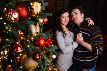 Young couple in love decorates a Christmas tree at home