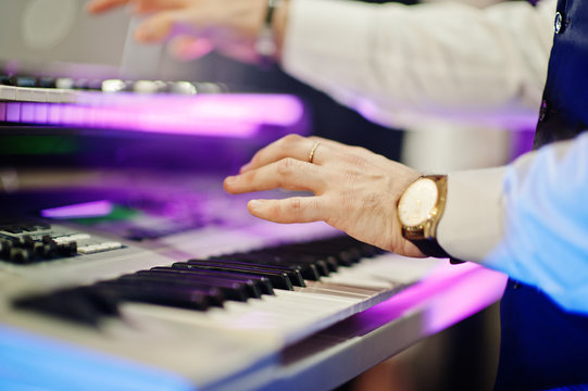 Hand of keyboardist on stage with lights.