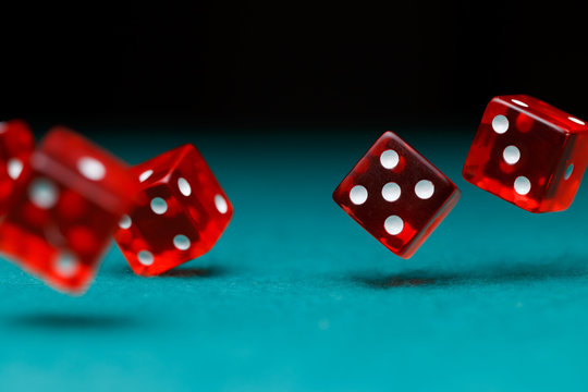 Picture of several red dice falling on green table