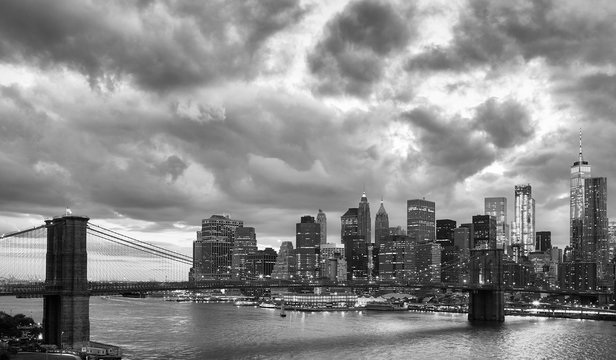 Fototapeta Black and white picture of Manhattan and Brooklyn Bridge with dramatic cloudscape at dusk, New York, USA.