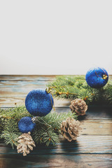 New Year and Christmas decorations Pine tree branches, cones, blue Christmas toys on a wooden background.