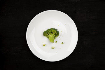 Fresh green broccoli in a white ceramic plate top view