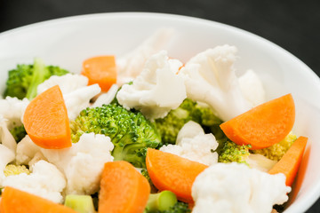 Fresh salad with raw broccoli, cauliflower and carrot in a white dish
