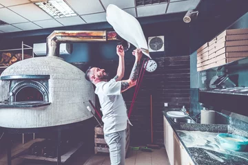 Poster Bebaarde pizzaiolo-chef luncht deeg in de lucht © marcin jucha