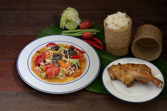 Papaya salad mix with salted crab (Som tum) with grill chicken and sticky rice in bamboo basketry and vegetables on banana leaf Thai food