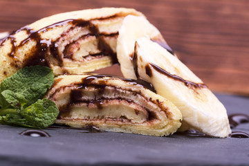 crepe with banana and chocolate on round slate stand