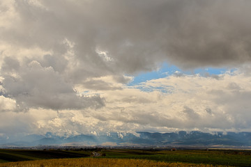 GREEN GRASSLAND AND STORM CLOUDS