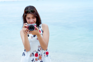 Asian woman taking photo with camera mirrorless at beach,Lifestyle hipster and travel relaxation,rest in summer season vacation concept, Selective camera focus