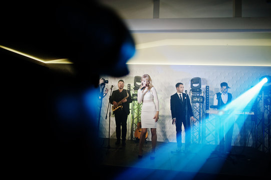 Musicial music live band performing on a stage with different lights.