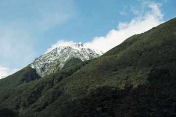 Obraz na płótnie Canvas Paisaje de picos de montañas nevados bajo un cielo azul con nubes