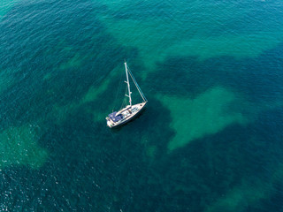 Vista aerea di una barca ormeggiata che galleggia su un mare trasparente. Immersioni relax e vacanze estive. Coste francesi, spiagge e rocce. Corsica. Francia
