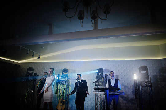 Musicial music live band performing on a stage with different lights.