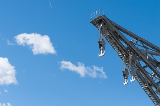 metal port crane with three hooks and blue sky