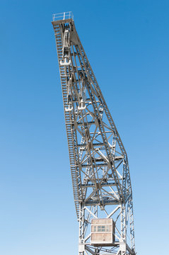 metal port crane with three hooks and blue sky