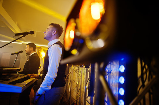 Musicial music live band performing on a stage with different lights. Keyboardist play.