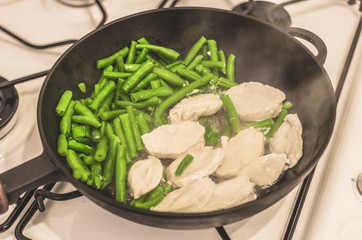 Green beans with chicken stewed on a cast-iron frying pan