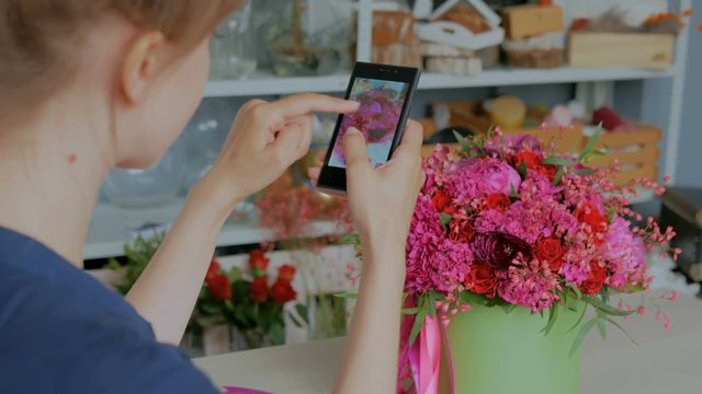 Professional floral artist, florist taking photo of her beautiful wedding bouquet with smartphone. Photography, technology and social media concept